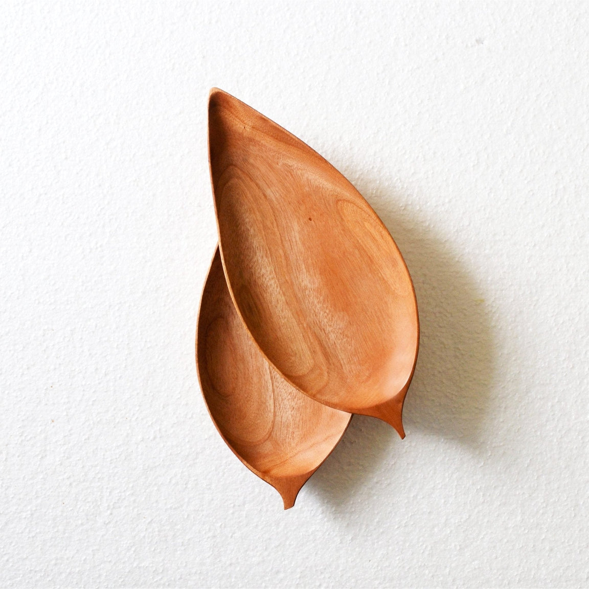 Two overlapping leaf shaped wooden platters, top view