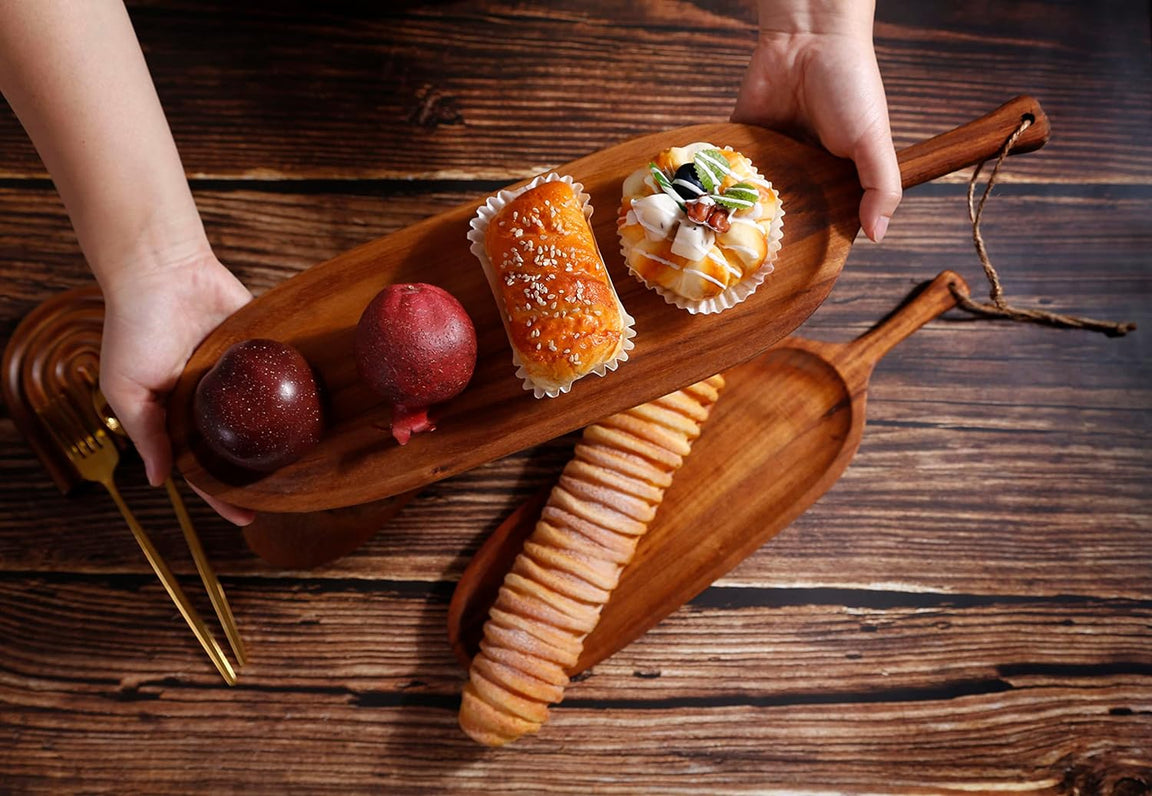 Hands placing long wooden platter with snacks on dark wood table