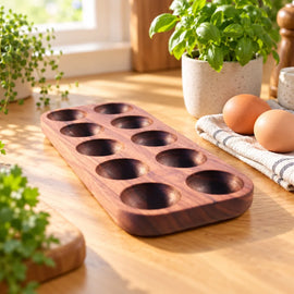 Mahogany ten-slot egg holder tray on a kitchen counter with eggs and a natural herb plant beside it