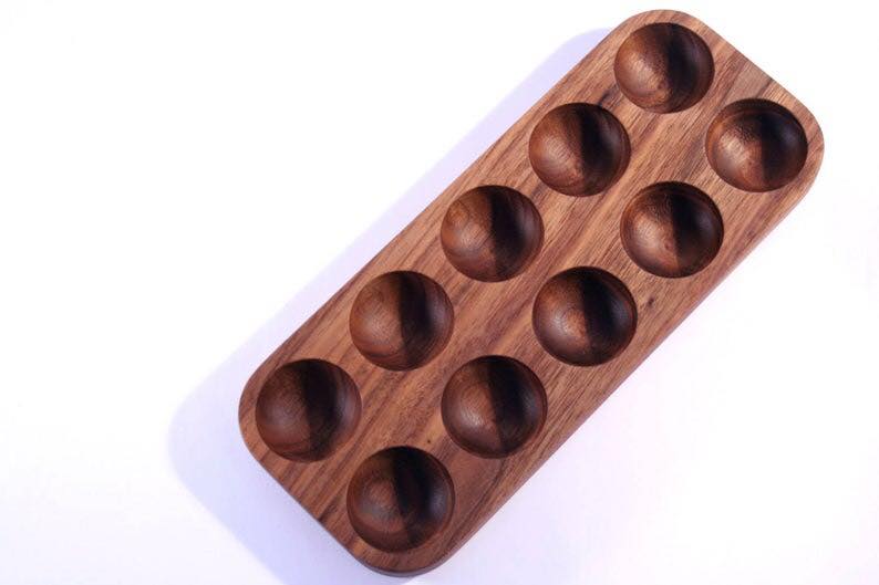 Empty mahogany wood egg tray with two rows of round slots, top view