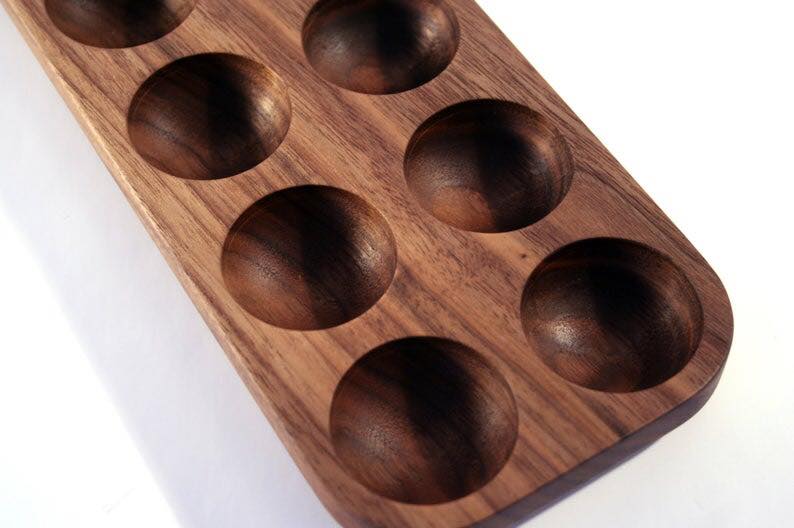 Close-up corner view of dark wood egg tray with smooth carved hollows