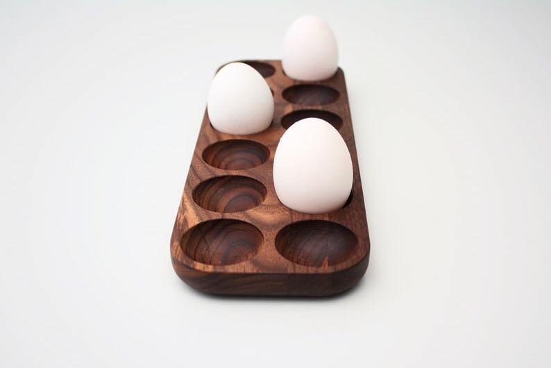 Small six slot wooden egg holder tray holding two white eggs