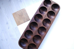 Dark wooden egg holder tray with ten slots on white table, top angled view