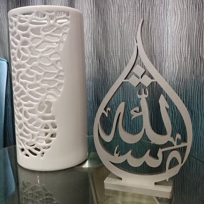 Teardrop shaped Mashaallah calligraphy table decor beside white vase