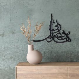 Black Min Fazli Rabbi calligraphy wall art on grey wall above vase