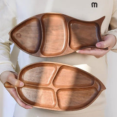 Person holding leaf shaped wooden platter tray below fish shaped tray, top view