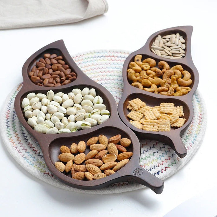 Four leaf shaped wooden dry fruit trays arranged together on woven mat