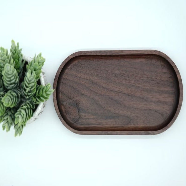 Top view of oval dark wood serving tray beside fern leaves