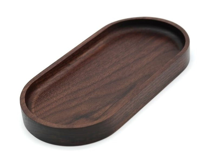 Dark oval wooden serving tray tilted at angle on white background
