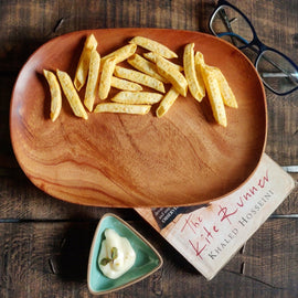 Oval wooden platter tray serving french fries on dark wooden table