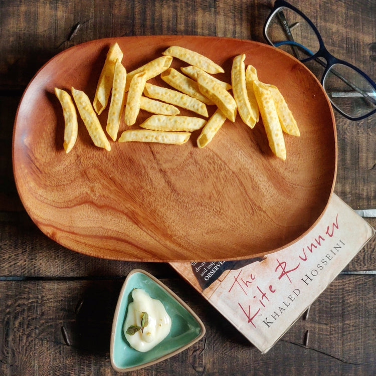 Oval wooden platter tray serving french fries on dark wooden table