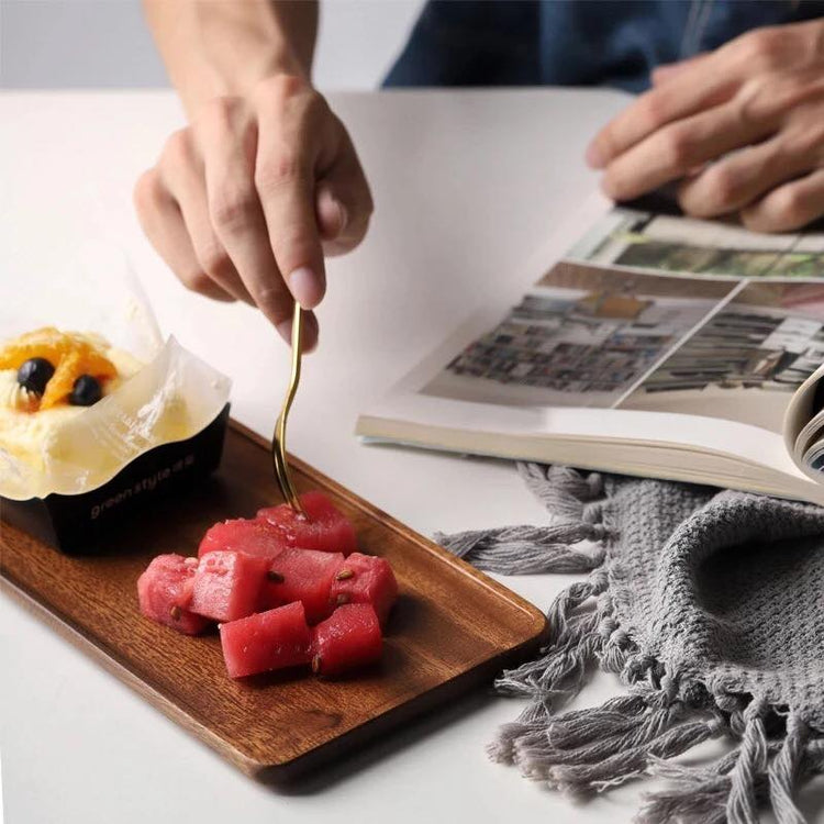 Wooden serving tray holding pink sweets and pastry beside open magazine