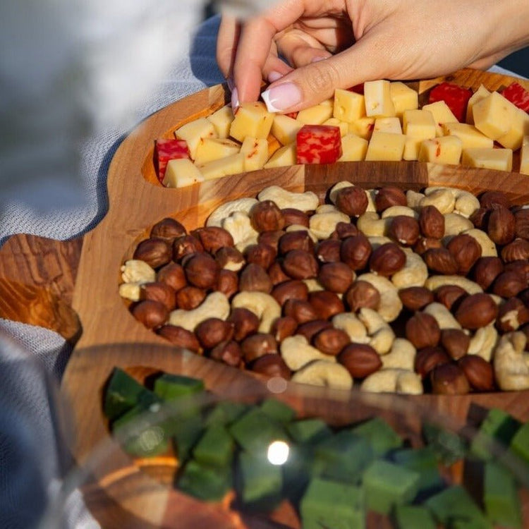 Close-up of pumpkin wooden snack tray filled with cheese cubes, nuts and chocolates