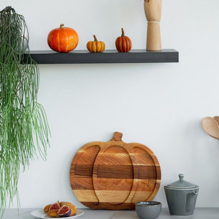 Pumpkin shaped striped wood serving tray displayed upright on kitchen counter