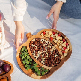 Pumpkin shaped solid wood serving tray with sectioned snacks at outdoor picnic