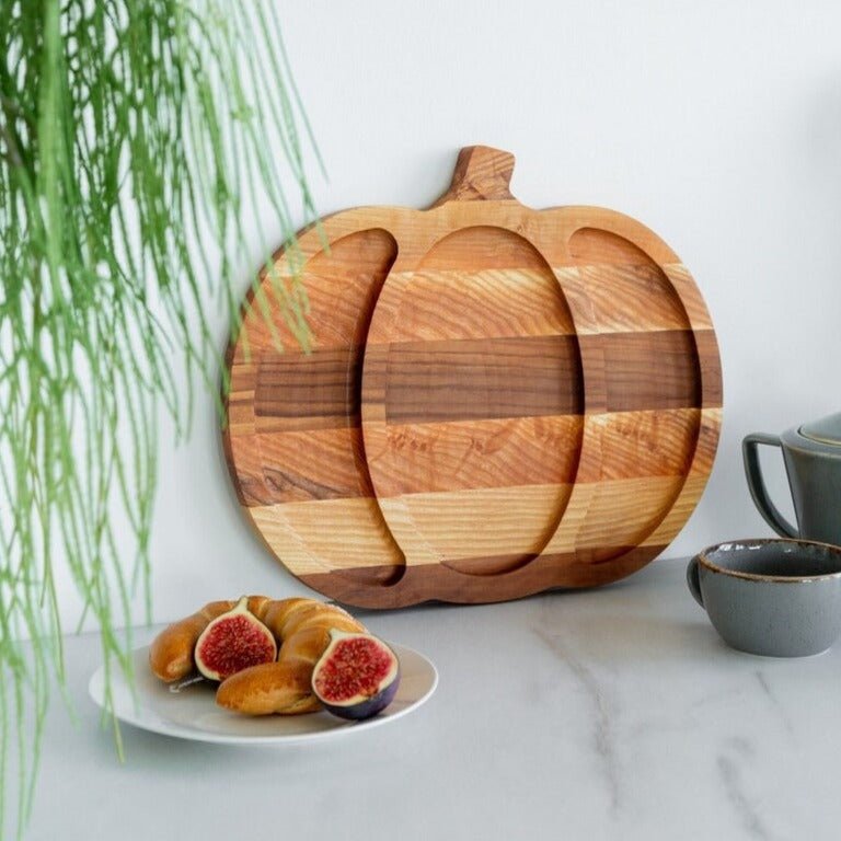 Close-up of pumpkin shaped solid wood serving tray with divided sections standing against wall
