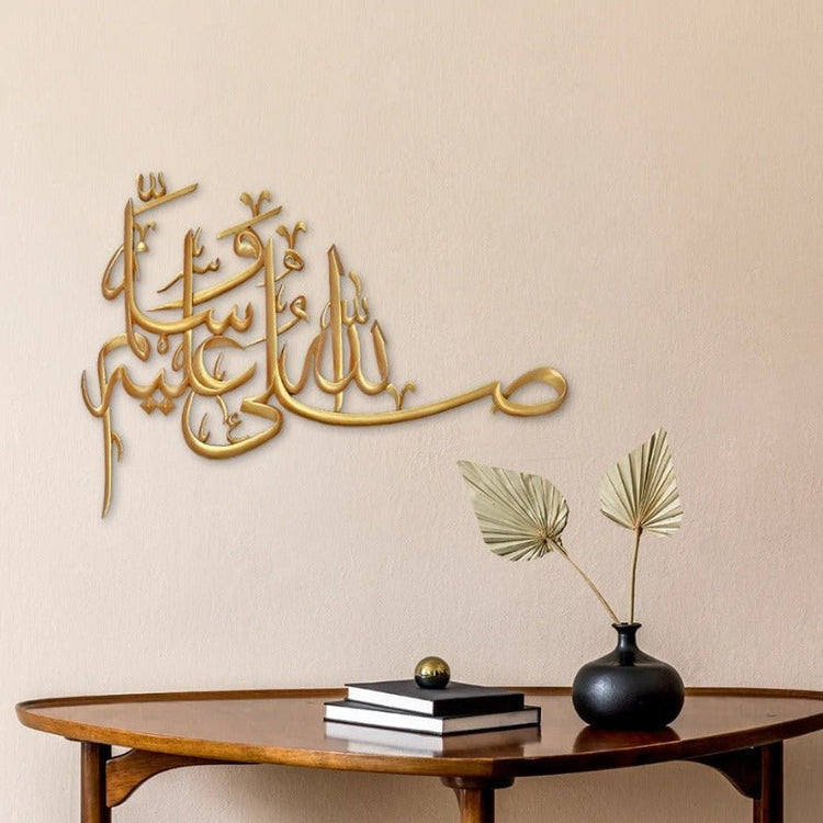 Gold Salawat laser cut calligraphy on warm beige wall above wooden table