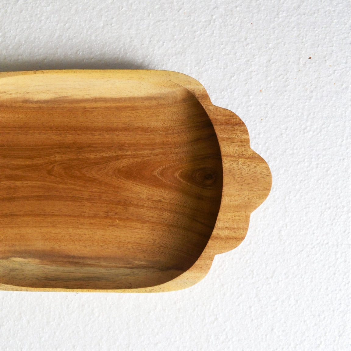 Close-up of scalloped handle end of rectangle wooden tray