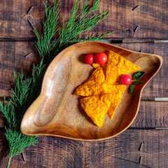 Shell shape wooden platter with nachos and tomatoes on rustic wooden table