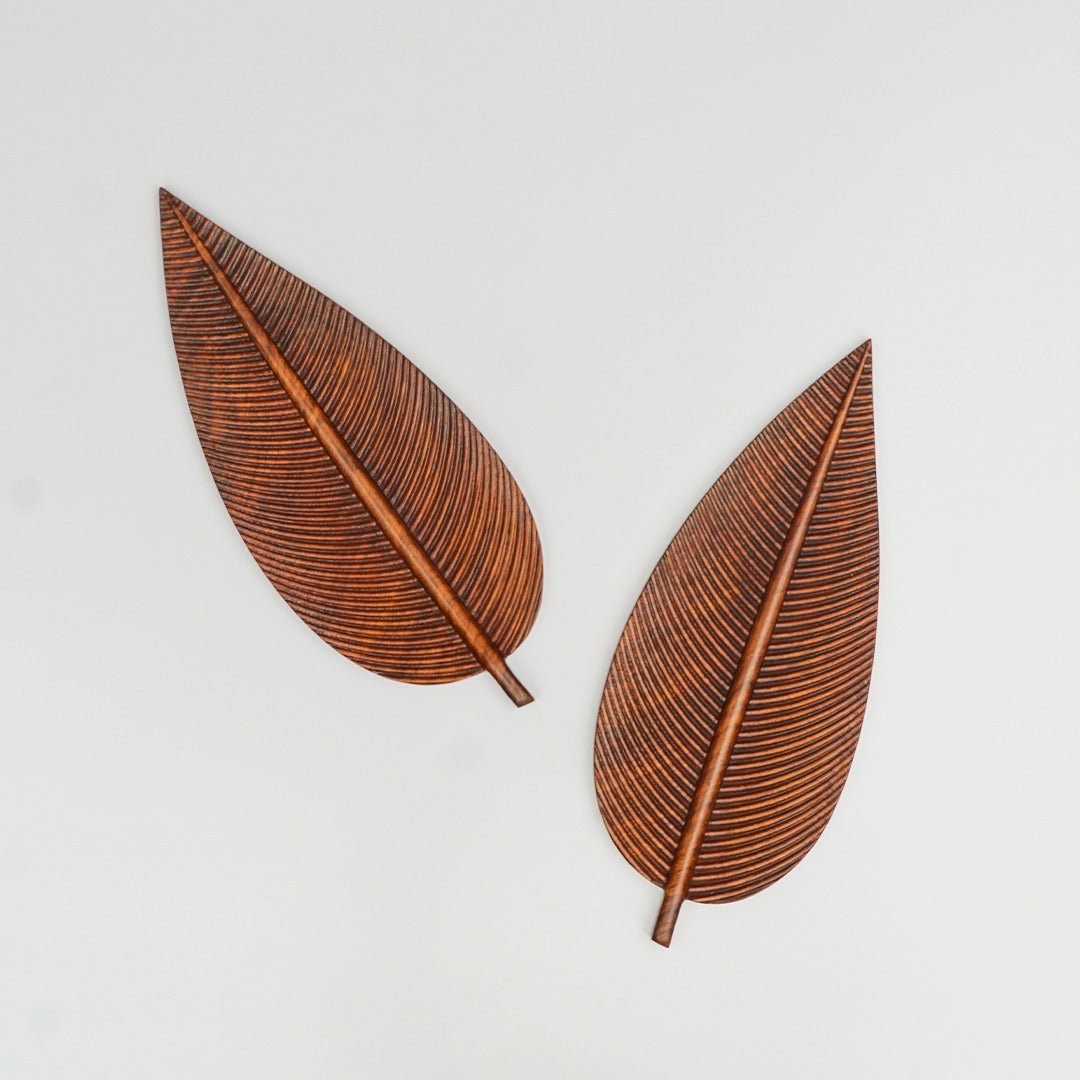 Two wooden leaf serving trays with stems and ribbed carving on grey background