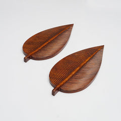 Two brown wooden leaf shaped serving trays with carved veins, angled view