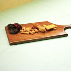 Low angle view of wooden paddle serving tray topped with crackers and dried fruit