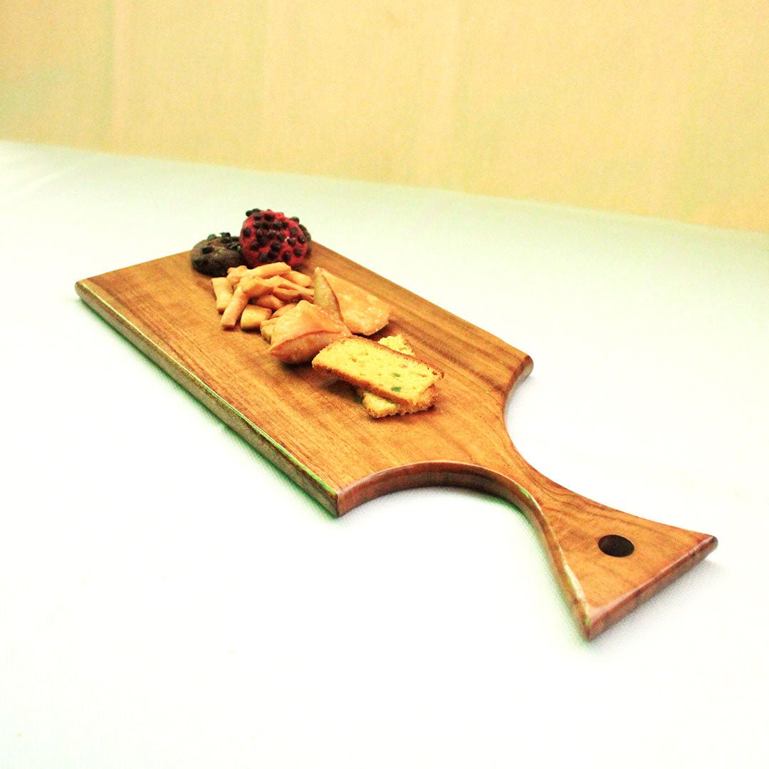 Angled view of rectangular wood serving tray with handle holding snacks on green surface