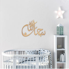 Gold Subhan Allah laser cut calligraphy on white nursery wall above crib