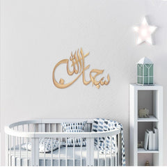 Gold Subhan Allah laser cut calligraphy on white nursery wall above crib