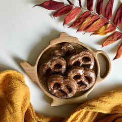 Teapot wooden tray filled with chocolate pretzels beside autumn leaves