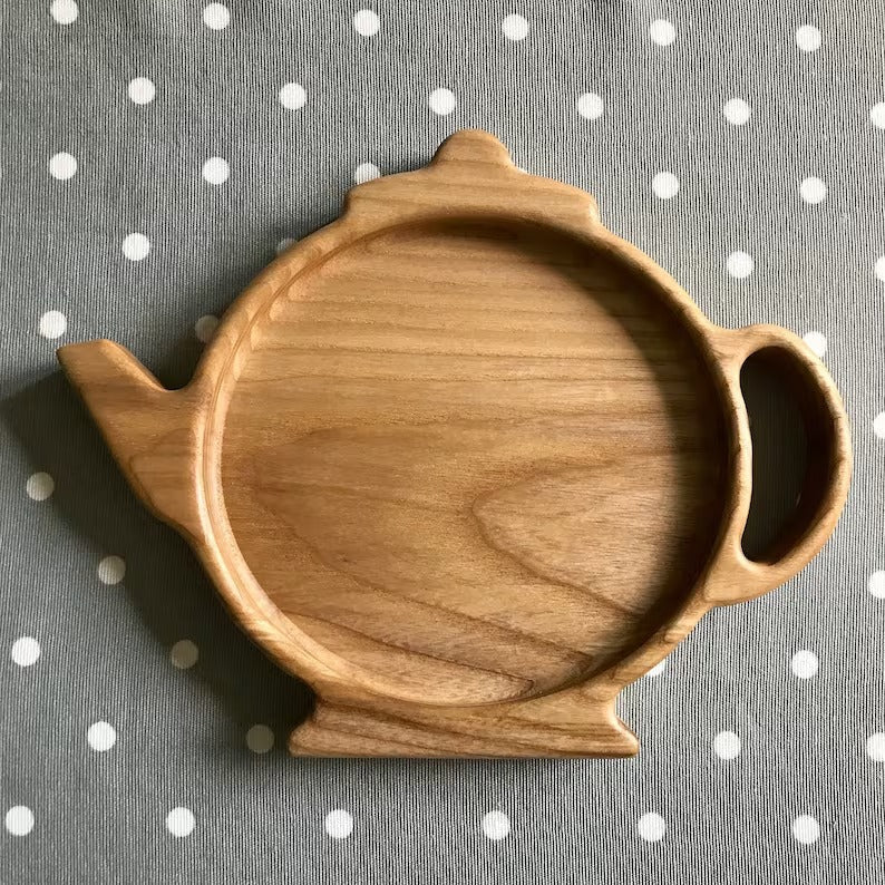Empty teapot shaped wooden tray on grey polka dot fabric, top view