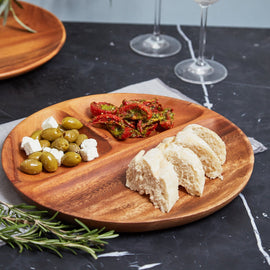 Three section round wooden platter with olives, dried tomatoes and bread