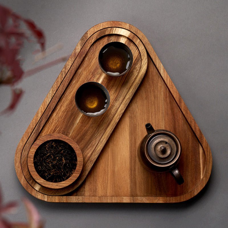 Top view of triangle shaped wooden platter tray with tea bowls and teapot