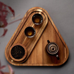 Top view of triangle shaped wooden platter tray with tea bowls and teapot
