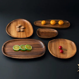 Five irregular oval wooden platters in different sizes on black background, top view