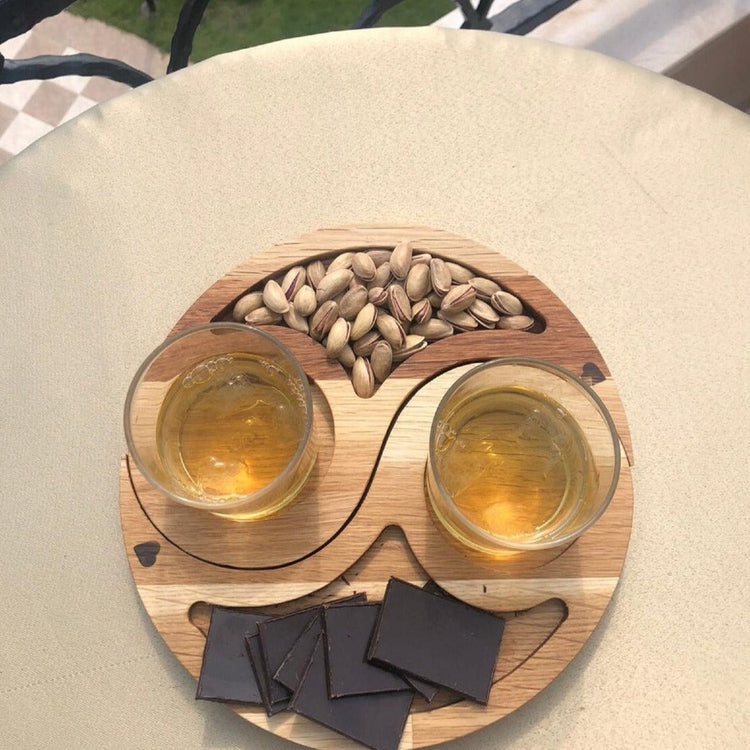 Yin yang wooden snack tray with nuts, drinks and dark chocolate pieces
